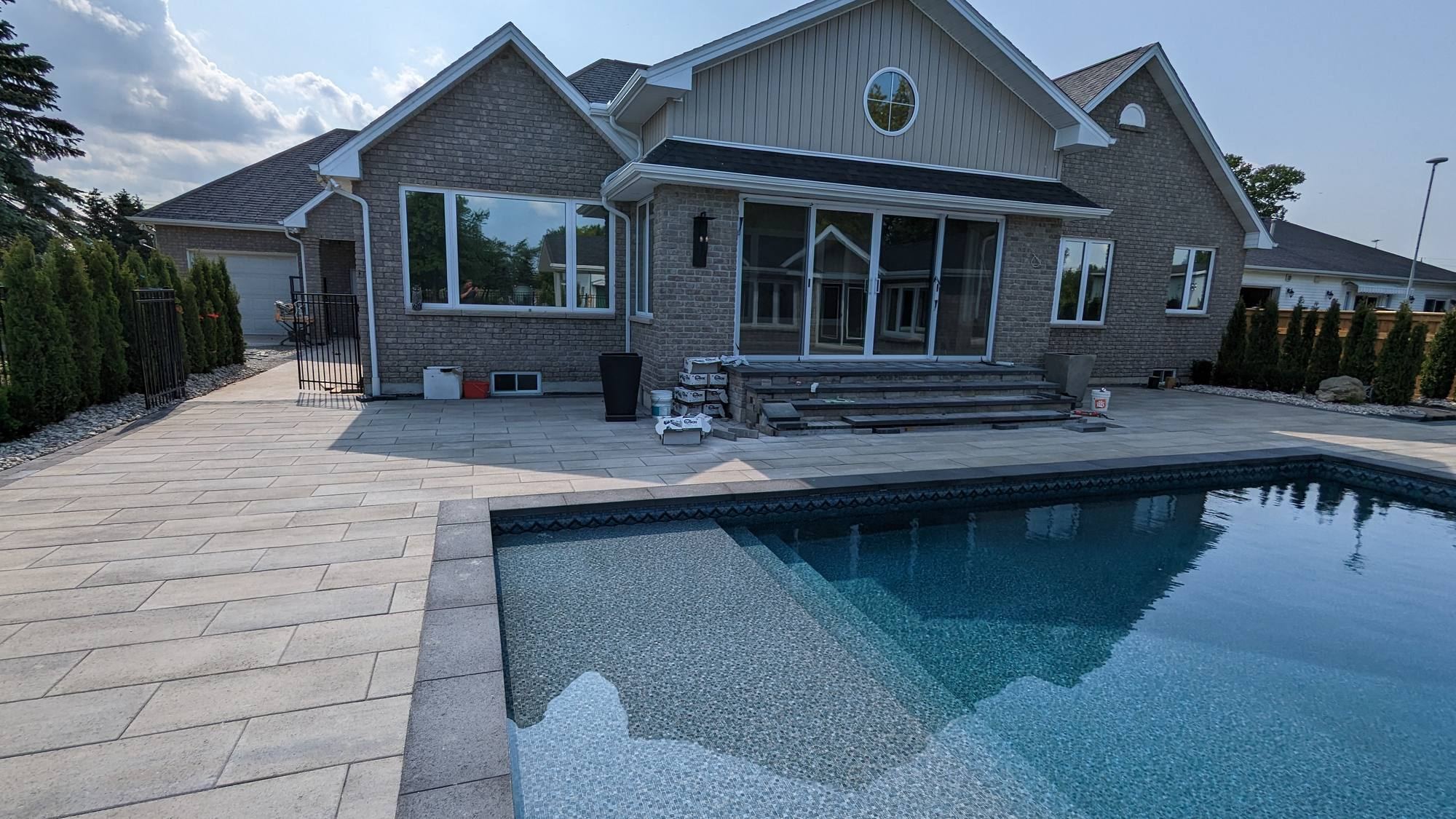 Backyard pool surrounded by a large paver patio
